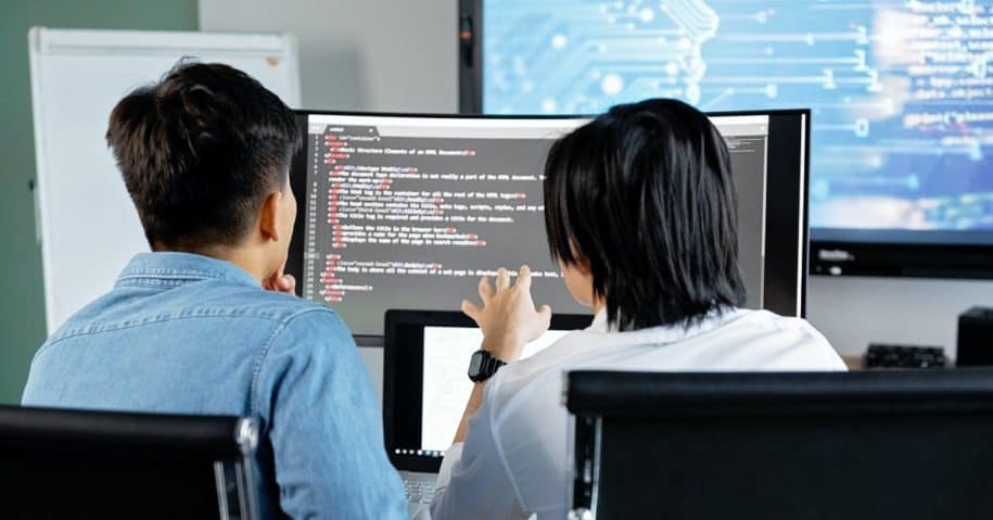 Two men working with code on computers